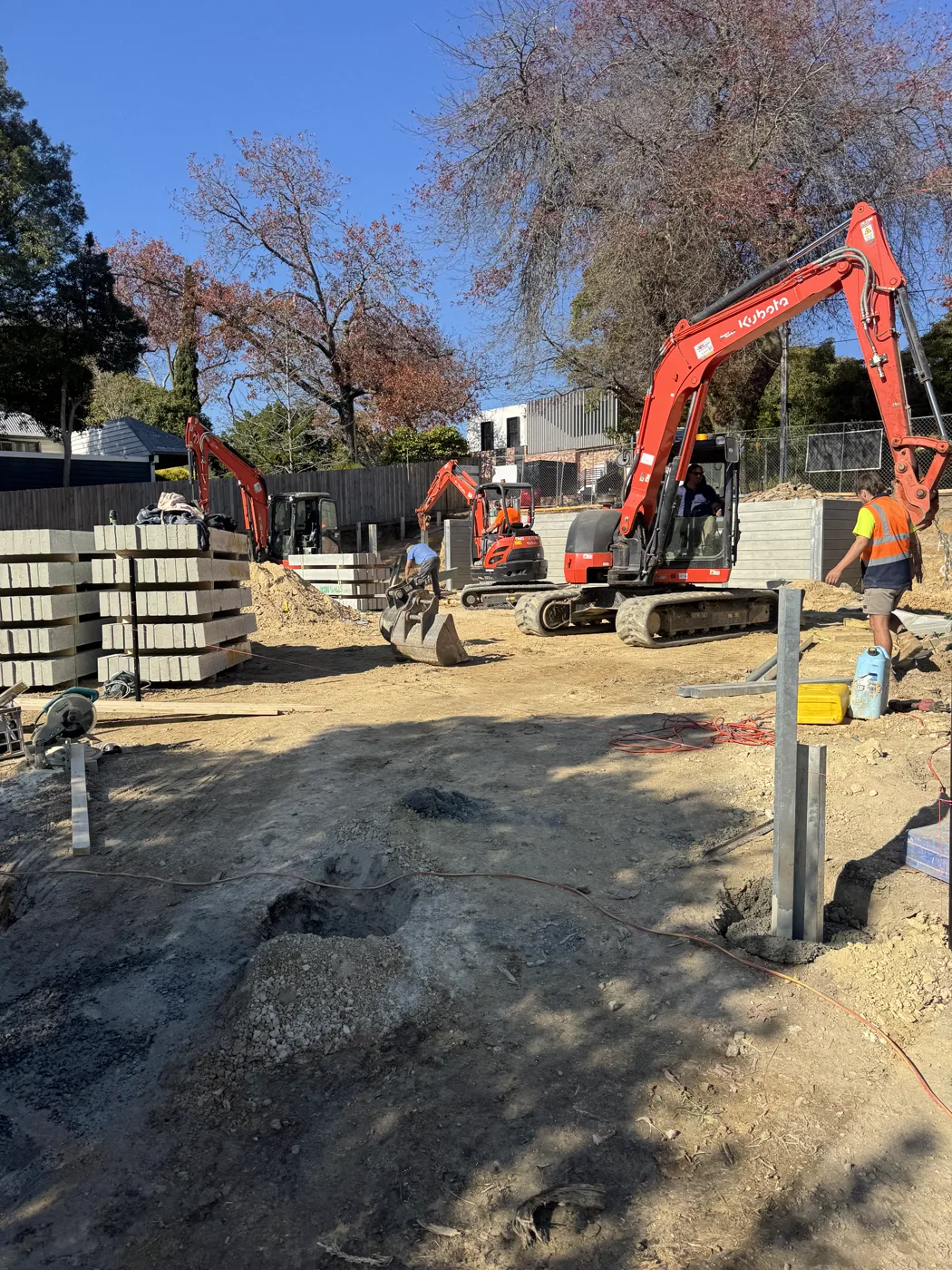 Align Excavation Group excavators and crew on site with sleepers staged for a retaining wall