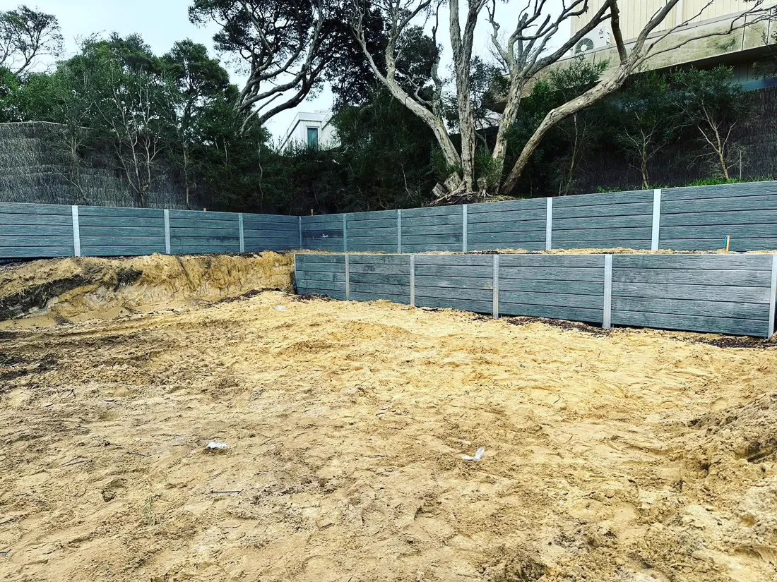 Engineered concrete sleeper retaining walls around a large building cut